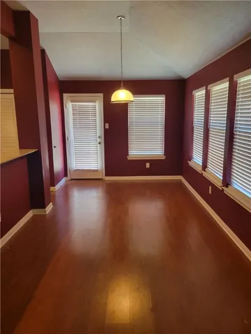 a view of an empty room with window and wooden floor