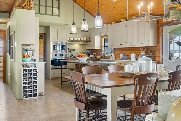 a kitchen with stainless steel appliances kitchen island granite countertop a table chairs sink and cabinets