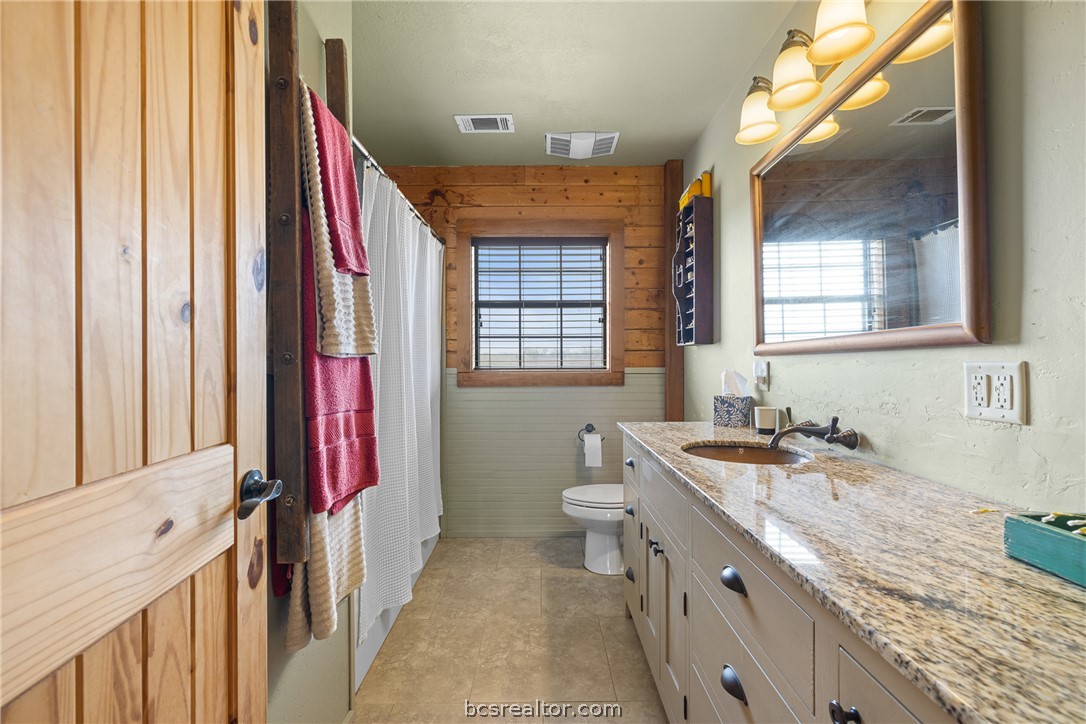 8501 Grassbur Road Bryan, TX 77808 - Photo 24 of 36 a bathroom with a granite countertop double vanity sink a mirror and a bathtub