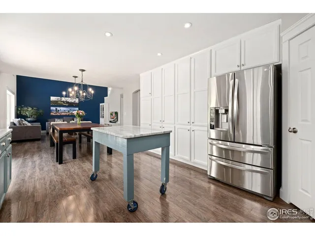 a kitchen with stainless steel appliances kitchen island granite countertop a refrigerator a stove a sink cabinets and a dining table