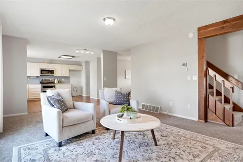 a kitchen with granite countertop a stove top oven a sink dishwasher and white cabinets with wooden floor