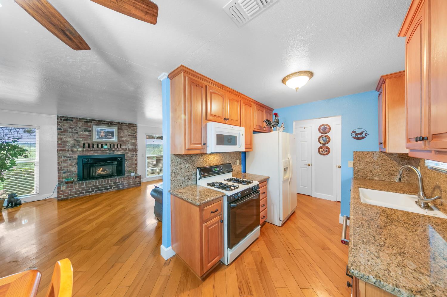1261 Jurgens Road Rescue, CA 95672 - Photo 42 of 74 a kitchen with stainless steel appliances granite countertop a stove top oven a sink dishwasher and a fireplace with wooden floor