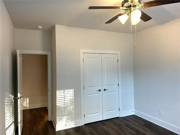 an empty room with wooden floor closet and fan