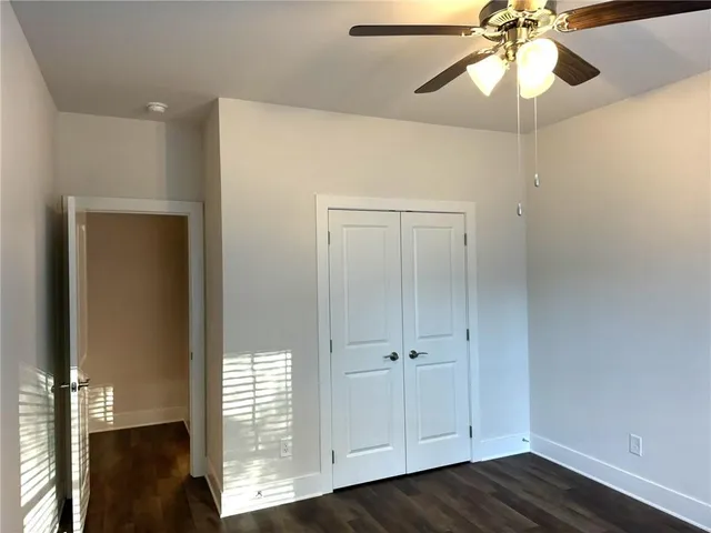 an empty room with wooden floor closet and fan