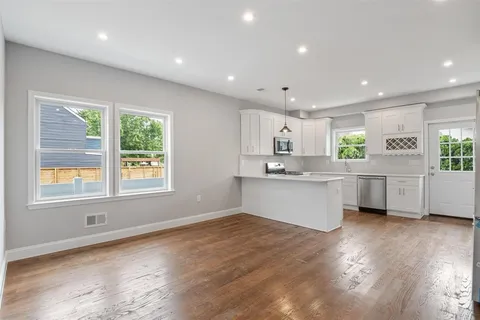 a large white kitchen with lots of counter space wooden floor and appliances