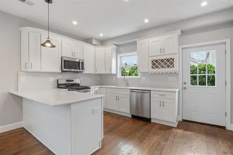 a kitchen with white cabinets appliances a sink and a window