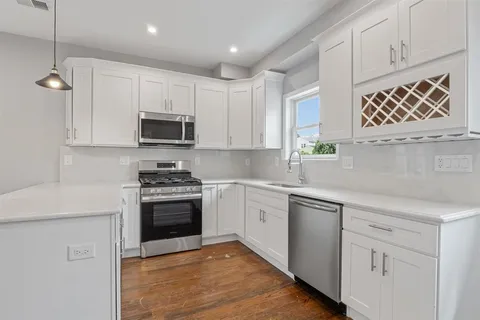 a kitchen with cabinets appliances a sink and a window