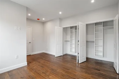 an empty room with wooden floor & closet area