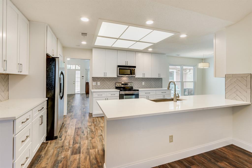 a large kitchen with granite countertop a large counter top stainless steel appliances and cabinets