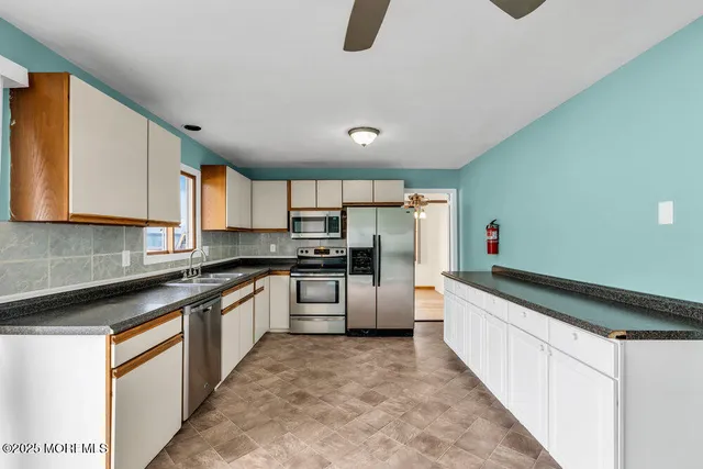 a kitchen with stainless steel appliances granite countertop a sink and dishwasher a stove top oven with white cabinets