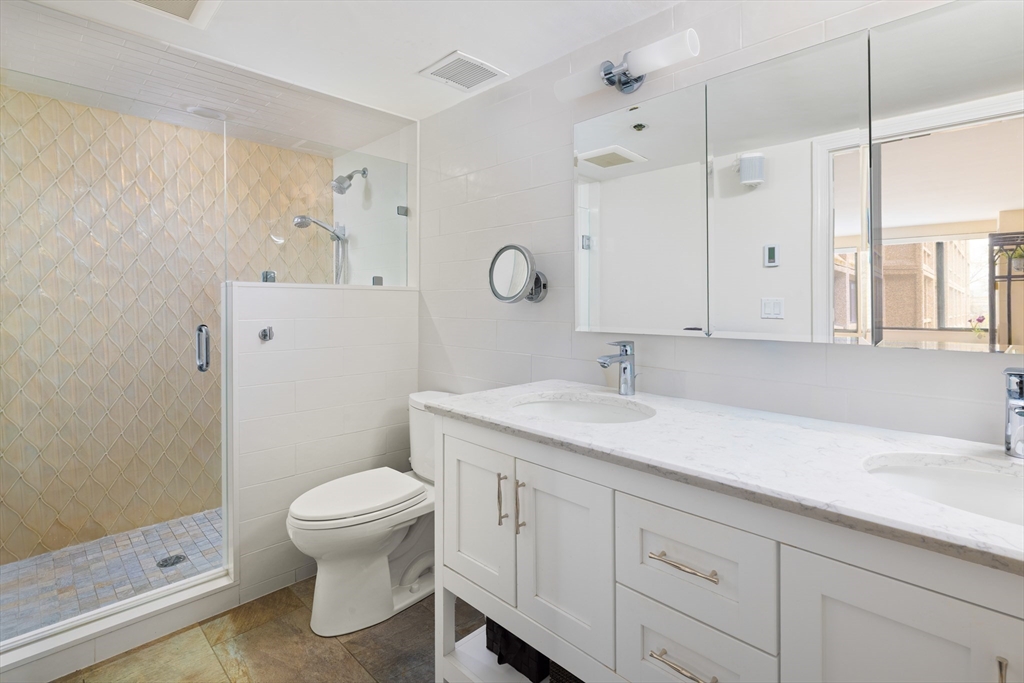 1731 Beacon Street, Unit 402 Brookline, MA 02445 - Photo 9 of 14 a bathroom with a granite countertop sink a toilet and a shower