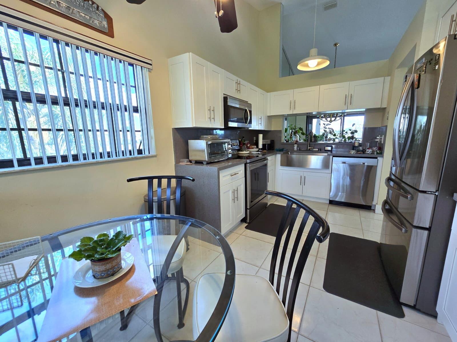 10870 Lakemore Lane, Unit 201 Boca Raton, FL 33498 - Photo 17 of 26 a kitchen with stainless steel appliances granite countertop a refrigerator sink stove and microwave