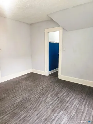a view of an empty room with wooden floor and closet
