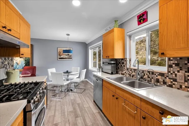 a kitchen that has a lot of cabinets stainless steel appliances and a large window