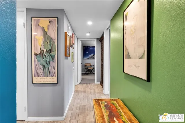 a view of a hallway with wooden floor and a bathroom