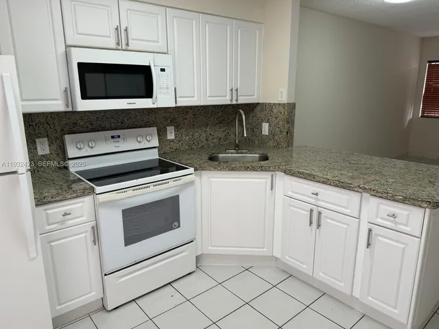 a kitchen with white cabinets and appliances