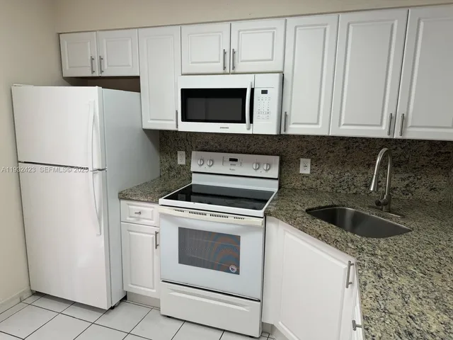 a kitchen with white cabinets and white appliances