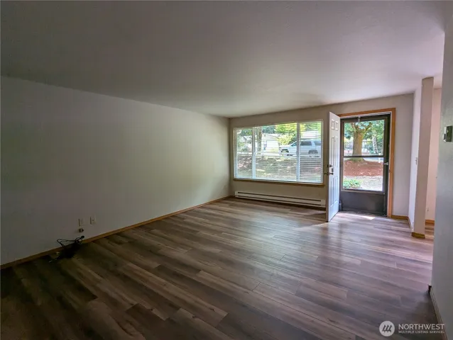 an empty room with wooden floor and windows