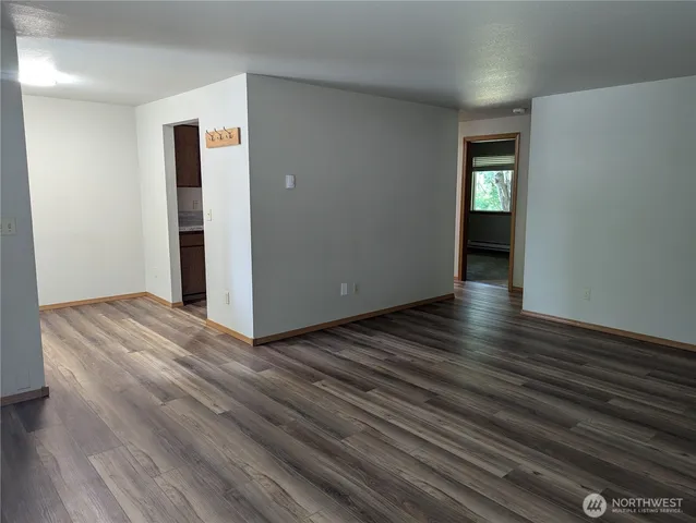 an empty room with wooden floor closet and windows