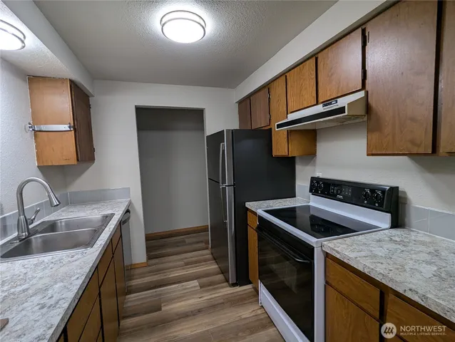a kitchen with granite countertop stainless steel appliances granite countertop a sink stove and refrigerator