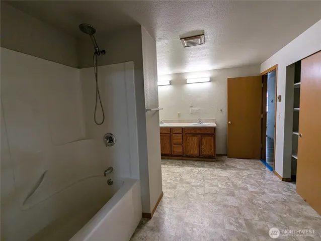 a bathroom with a tub sink shower and a mirror