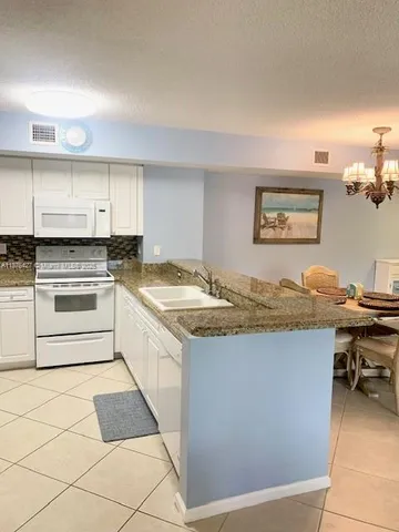 a living room with stainless steel appliances kitchen island granite countertop furniture and a rug
