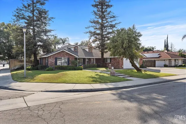a view of a house with a big yard plants and large trees
