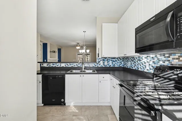 an empty room with a chandelier fan and windows