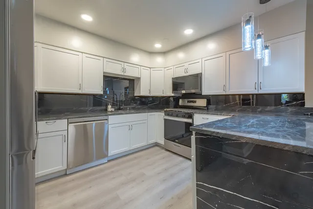 a kitchen with stainless steel appliances granite countertop a sink stove microwave and cabinets