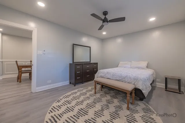 a spacious bedroom with a bed a chandelier and a dresser