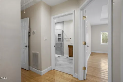 a view of a hallway with wooden floor and a bathroom
