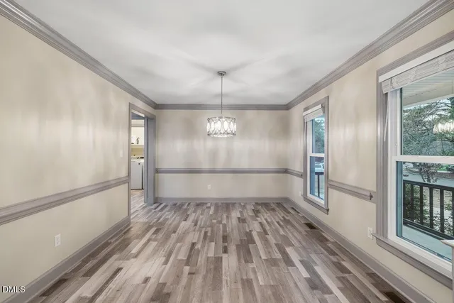 a view of a hallway with wooden floor and a bathroom