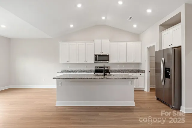 a kitchen with stainless steel appliances granite countertop a stove a refrigerator and a microwave