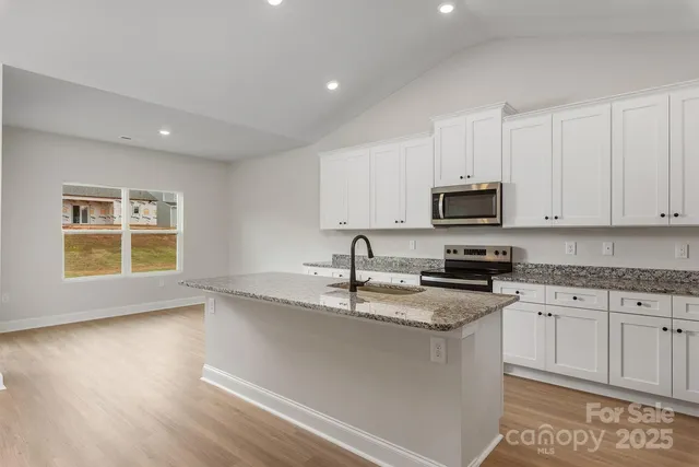 a kitchen with stainless steel appliances granite countertop a sink a stove a microwave and cabinets