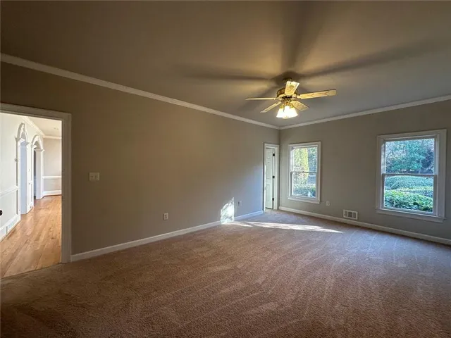 an empty room with windows and ceiling fan