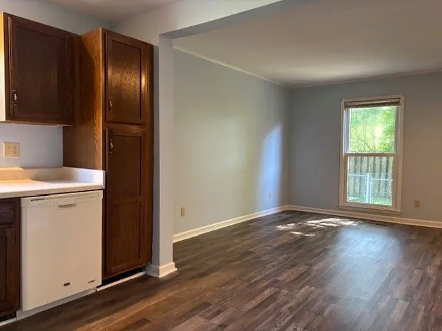 an empty room with wooden floor cabinet and windows