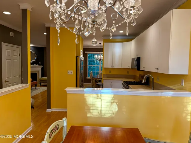 a view of a kitchen with stainless steel appliances granite countertop a sink a stove cabinets and a dining table