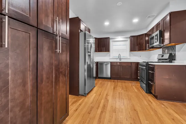 a large kitchen with stainless steel appliances lots of counter space and wooden floor