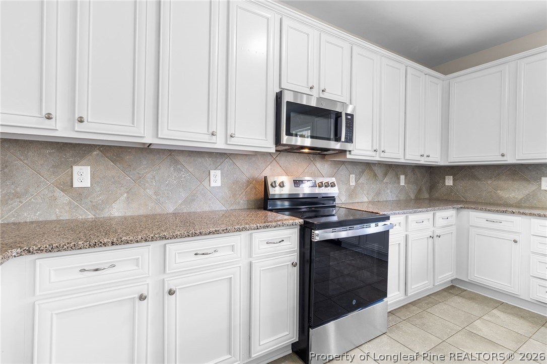 50 Huzzas Circle Cameron, NC 28326 - Photo 15 of 39 a kitchen with granite countertop white cabinets and stainless steel appliances