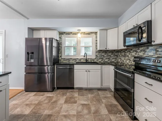 a kitchen with granite countertop a refrigerator stove and sink
