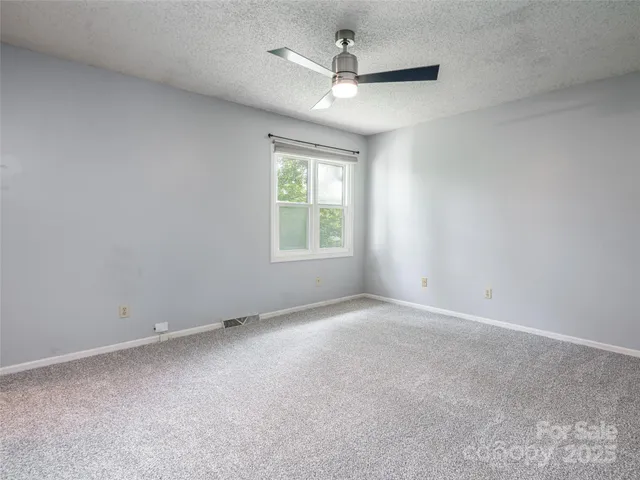 an empty room with a ceiling fan and windows