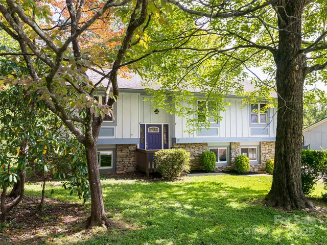 a view of a house with backyard and a tree