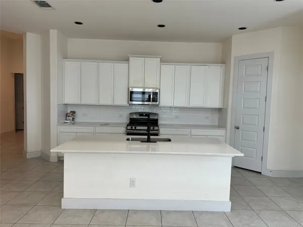 a kitchen with kitchen island white cabinets and stainless steel appliances