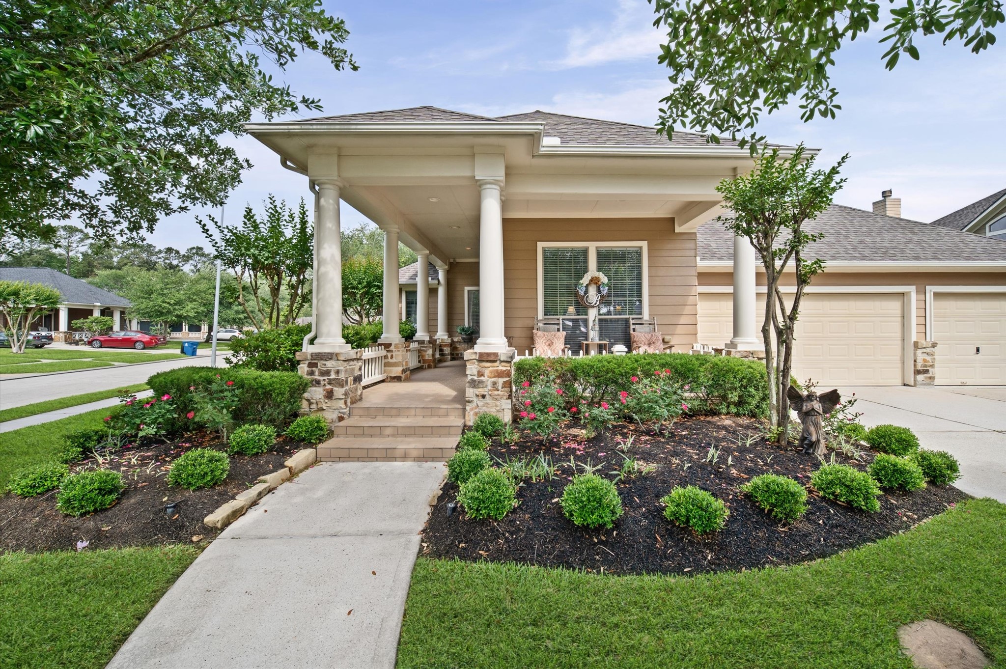 Charming single-story home with a welcoming front porch supported by elegant columns. The manicured landscaping features lush greenery and vibrant flowers, enhancing curb appeal. A spacious driveway leads to a three-car garage, offering ample parking. Ideal for those seeking a blend of style and comfort.