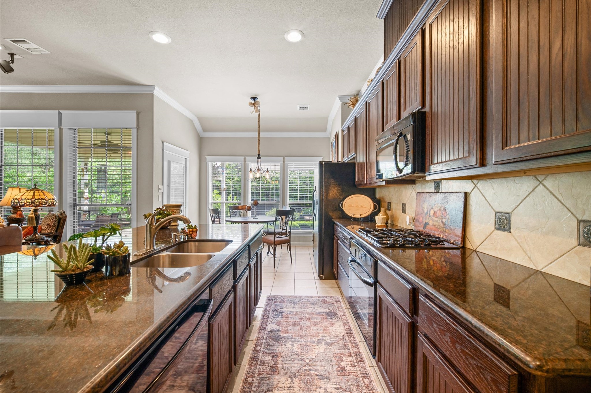 1603 Claytons Bend Court Spring, TX 77386 - Photo 19 of 38 This kitchen features rich wooden cabinetry, granite countertops, and modern appliances. An open layout connects to a bright dining area with large windows, offering a view of the lush greenery outside.