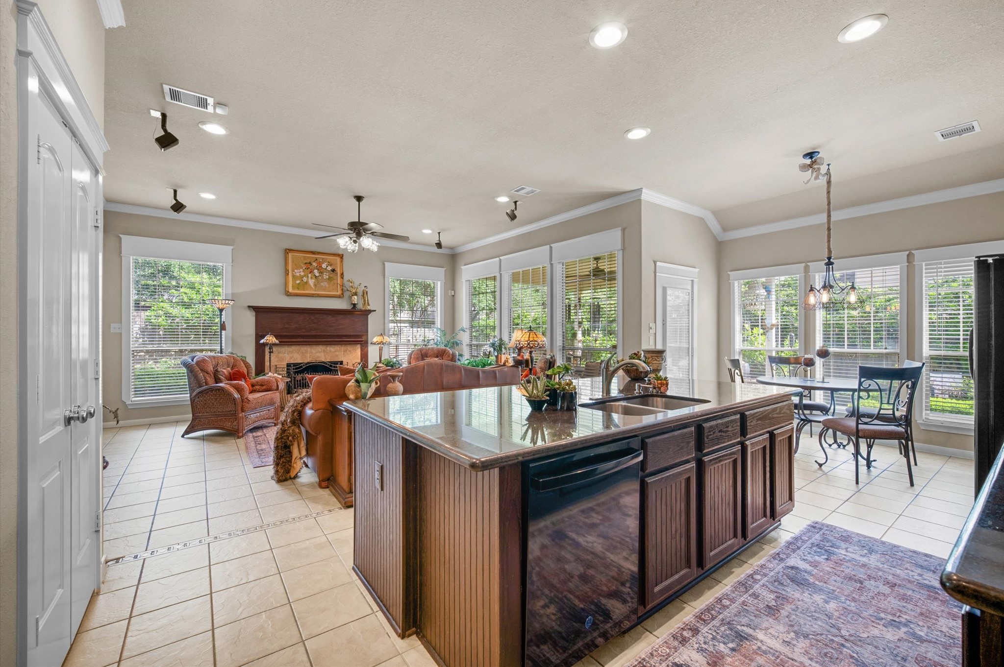 1603 Claytons Bend Court Spring, TX 77386 - Photo 20 of 38 This spacious open-concept living area features a large kitchen island with dark wood cabinets, a cozy seating area with a fireplace, and abundant natural light from multiple windows. There's also a dining nook with garden views, creating a warm and inviting atmosphere.