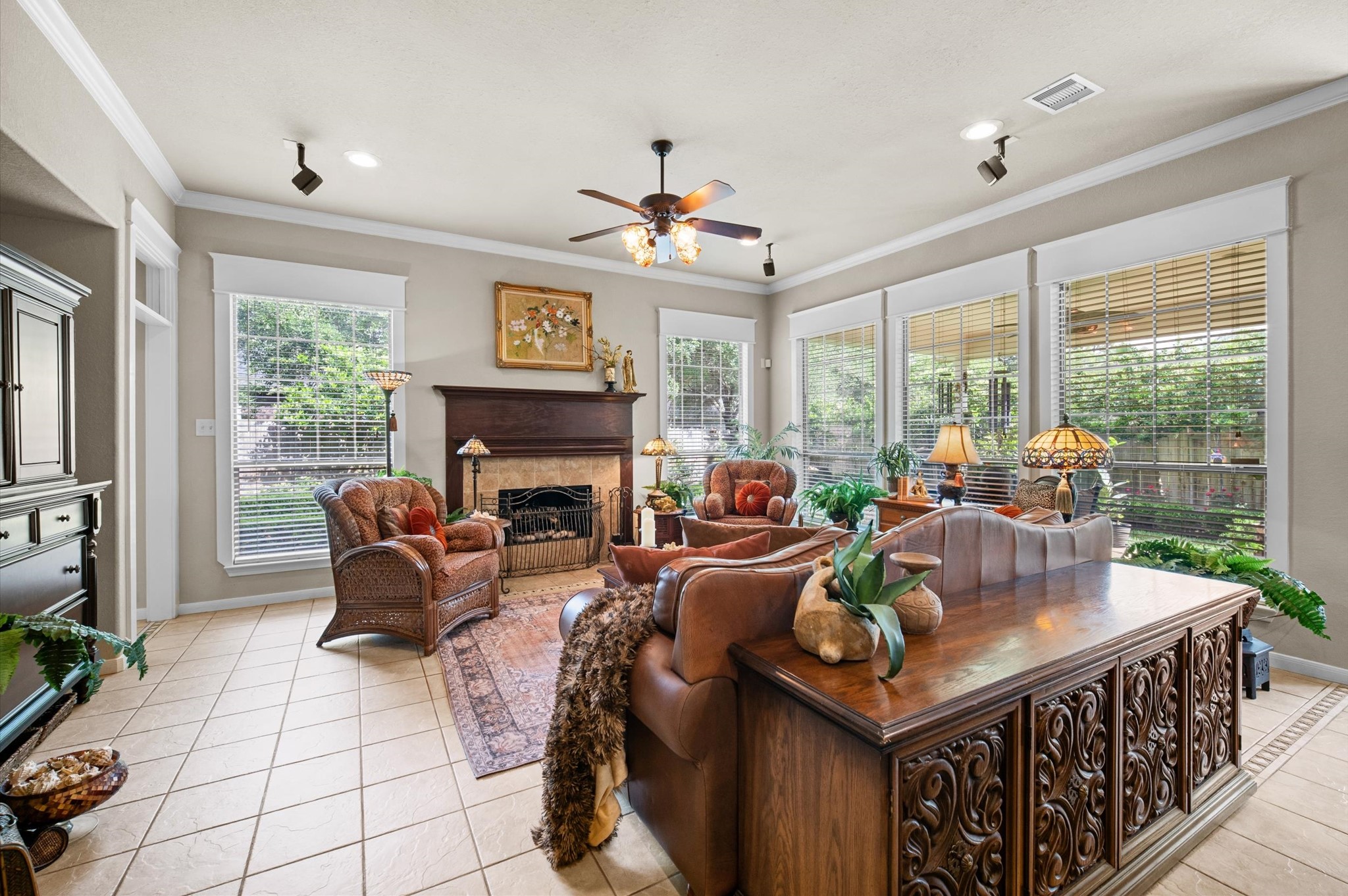 1603 Claytons Bend Court Spring, TX 77386 - Photo 21 of 38 This inviting living room features large windows allowing abundant natural light, a cozy fireplace, tiled flooring, and elegant decor. The space offers a comfortable seating arrangement and a view of the garden, creating a warm and welcoming atmosphere.