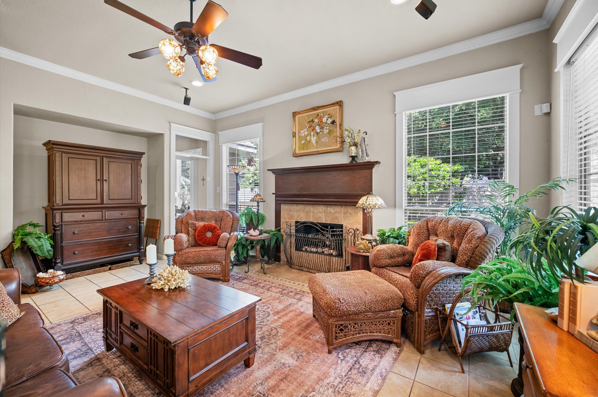 1603 Claytons Bend Court Spring, TX 77386 - Photo 22 of 38 This cozy living room features a warm, inviting atmosphere with a classic fireplace, large windows offering natural light, and elegant wooden furniture. The space is accented with houseplants and tasteful decor, perfect for relaxing or entertaining.