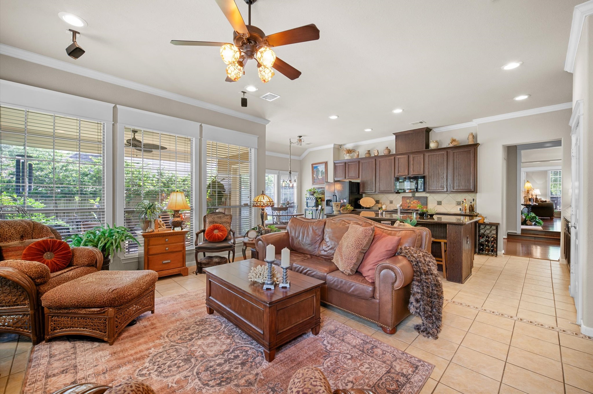 1603 Claytons Bend Court Spring, TX 77386 - Photo 23 of 38 This open-concept living space features a cozy seating area with a leather sofa and armchairs, large windows providing natural light, and a view of the patio. The kitchen boasts dark wood cabinets, a center island, and modern appliances, seamlessly connecting to the living area.