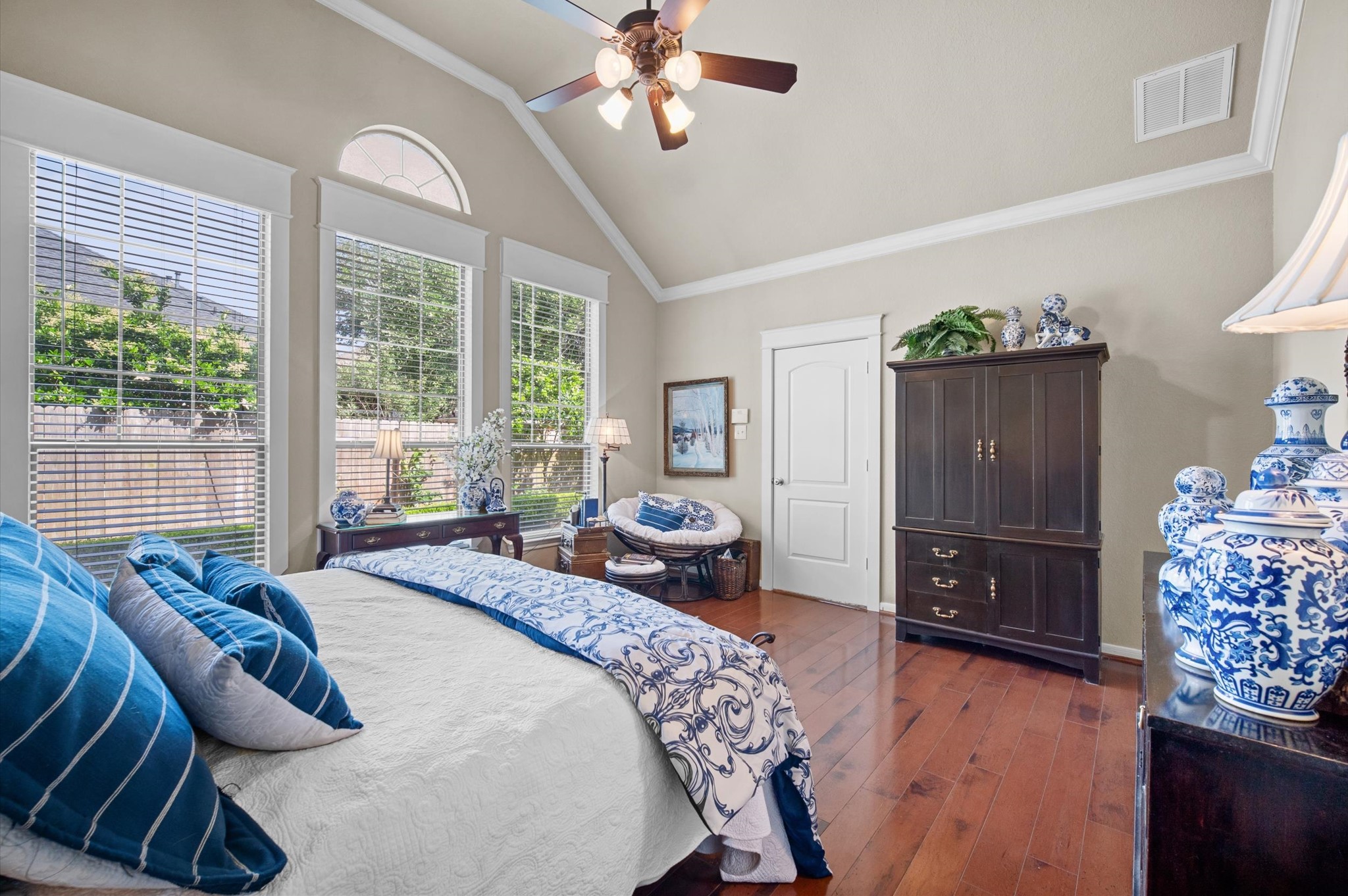 1603 Claytons Bend Court Spring, TX 77386 - Photo 25 of 38 This inviting bedroom features large windows with abundant natural light, elegant blue and white decor, and warm wood flooring. The space includes a comfortable bed, ceiling fan, and classic wooden furniture, creating a cozy and stylish atmosphere.